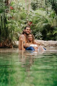 un homme et une femme assis dans l'eau dans l'établissement Nahouse Jungle Lodges, à Tulum