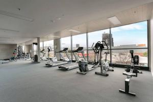 a gym with a bunch of treadmills and elliptical machines at Prestige 2bd Apartment Gym/Pool in Adelaide