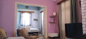 een woonkamer met roze muren en een televisie bij TWO-BEDROOMS in GREEK VINTAGE HOME with shared Bathroom in Korinthos