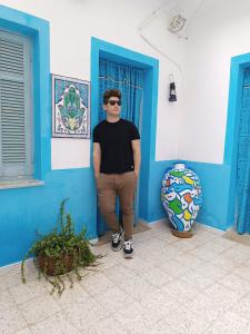 a man standing in front of a blue wall at Dar Hkaïem in Hammam Sousse