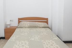 Bett mit einem Kopfteil aus Holz und einem Nachttisch in der Unterkunft Estirpe, 2º-4 in Cullera