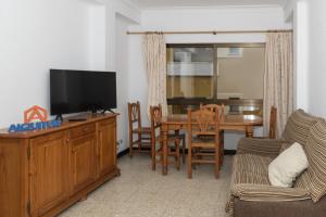 a living room with a television and a table with chairs at Estirpe, 2º-4 in Cullera