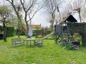 een park met een speeltuin met banken en een glijbaan bij Vakantieoord "de Peppelhoeve" in Koudekerke