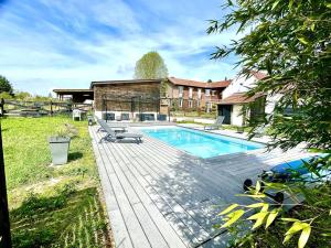 a swimming pool with a wooden deck next to a house at Le Paddock - Chambres et table d'hôtes in Le Déluge