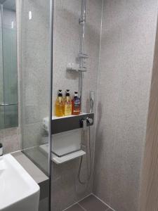 uma casa de banho com um chuveiro e 2 garrafas numa prateleira em Sokcho Summitbay 1701 "Ocean View" em Sokcho