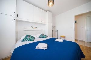 - une chambre avec un lit bleu et des serviettes dans l'établissement Apartman Nane, à Solin