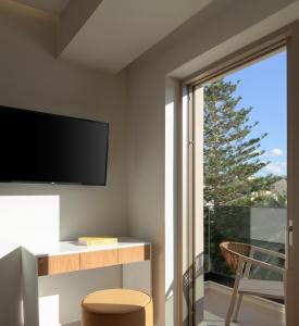 a living room with a tv and a sliding glass door at Ostria Deluxe Suite Studio in Rethymno Town
