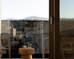 uma mesa com um copo de vinho e uma janela em Matareva Suites - Ostria Deluxe Suite Studio em Retimno