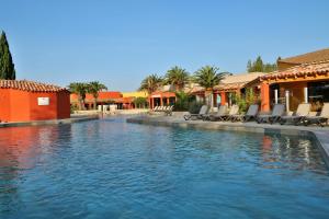 - une piscine dans un complexe avec des chaises et des bâtiments dans l'établissement SOWELL HOTELS L'Olivier, à Arles