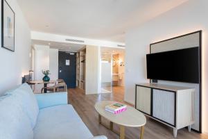 sala de estar con sofá azul y TV de pantalla plana en Suites del Mar by Melia, en Alicante