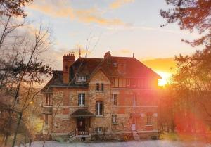 una casa vieja con la puesta de sol en el fondo en Le Manoir du Cerf, en Gaillon