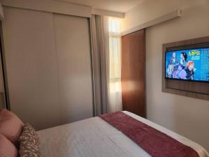 une chambre avec un lit et une télévision au mur dans l'établissement Apartamento Park Sul, à Brasilia