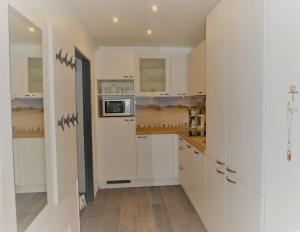 a kitchen with white cabinets and a microwave at Burgtiefe Südstrand "Sorglos" in Fehmarn