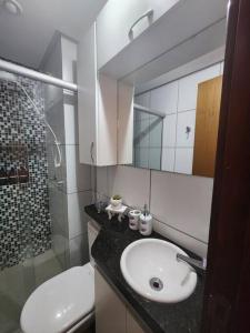 La salle de bains est pourvue d'un lavabo, de toilettes et d'un miroir. dans l'établissement Apartamento Park Sul, à Brasilia