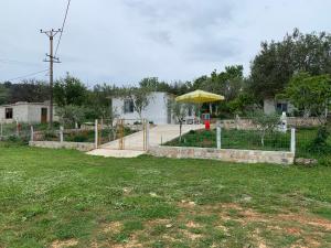 a garden with a fence and a yellow umbrella at Villas Ermali in Ksamil