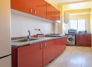 a kitchen with red cabinets and a sink at Appartement 2 chambre 5min Aéroport in Marrakech