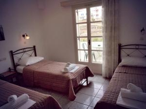 una camera d'albergo con due letti e una finestra di Nikolas ios Village a Ios Chora
