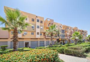 una fila de edificios de apartamentos con palmeras y arbustos en Appartement 2 chambre 5min Aéroport en Marrakech