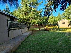 a house with a fence and a yard with trees at Ukutula Resort in Dullstroom