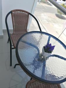 een glazen tafel met een boeket paarse bloemen erop bij Hotel Inkayacu in Paracas