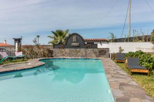 einen Pool in einem Garten mit einer Steinmauer in der Unterkunft Palmeira House - Fernandes Cottage in Ponta Delgada