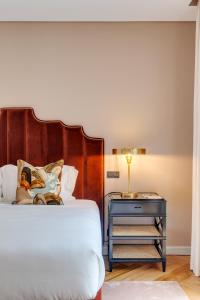 een bed met een houten hoofdeinde en een blauwe nachtkastje bij Portie Deluxe Suites by DA'HOME in Porto
