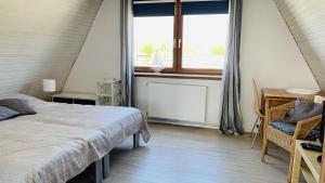 Schlafzimmer mit einem Bett, einem Fenster und einem Schreibtisch in der Unterkunft Sternkieker in Kappeln
