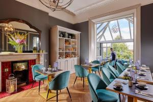 una sala da pranzo con tavoli, sedie e camino di Ariel House a Dublino