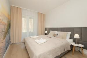 a bedroom with a white bed with a white flower on it at Plażowa Park Apartment with Garden by Noclegi Renters in Międzywodzie
