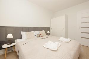 a white bedroom with a large bed with towels on it at Plażowa Park Apartment with Garden by Renters in Międzywodzie