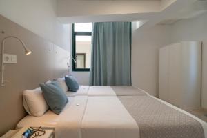 1 dormitorio con 1 cama blanca grande con almohadas azules en Sabbia Suites Arrecifeando, en Arrecife
