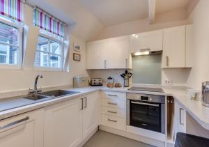 a kitchen with white cabinets and a sink and a window at 4 Dormy House in Brancaster