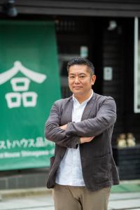 Un uomo sta in piedi con le braccia incrociate di Guest House Shinagawa-shuku a Tokyo