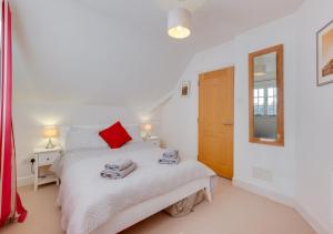 a white bedroom with a bed with towels on it at 4 Dormy House in Brancaster
