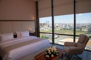 a bedroom with a bed and a chair and windows at Jeddah Homes Boutique Hotel in Amman