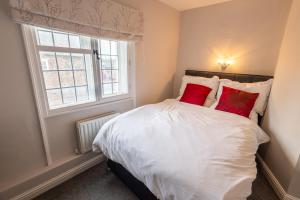 Un dormitorio con una cama con almohadas rojas y una ventana en Bridge Street Views en Chester