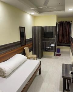 1 dormitorio con 1 cama y TV. en Atithi Guest House, en Siliguri
