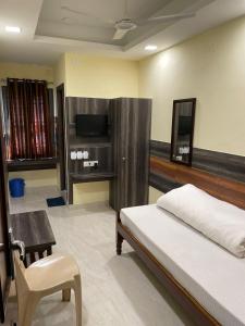 - une chambre avec un lit, une télévision et une chaise dans l'établissement Atithi Guest House, à Siliguri