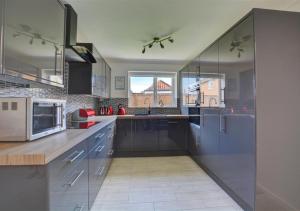 cocina grande con armarios azules y ventana grande en 8 Augusta Court, en Sheringham