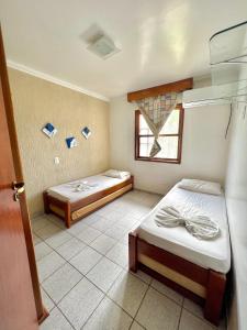 Habitación con 2 camas y ventana en Apto no condomínio Taperapuan Village, en Porto Seguro