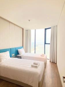 Cette chambre comprend deux lits et une grande fenêtre. dans l'établissement A La Carte Hạ Long Bay View 2, à Hạ Long