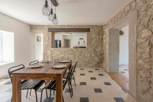 Mas Picholine - Maison pour 10 avec piscine في Saint-Jean-de-Maruéjols-et-Avéjan: غرفة طعام مع طاولة وكراسي خشبية