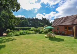 a garden with a picnic table and an umbrella at Acorn Cottage in Briston