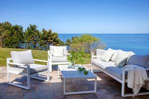 a patio with two chairs and a couch and a table at Impresionante villa sobre el mar en el mismo Comillas in Comillas