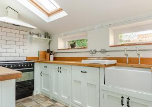 a kitchen with white cabinets and a sink at Albert Cottage in Holt