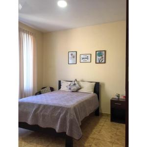 um quarto com uma cama e duas fotografias na parede em Bonita casa acogedora em Cochabamba