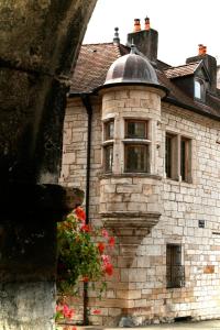 un antiguo edificio de piedra con una ventana y flores en Maison La Tourelle, en Baume-les-Dames