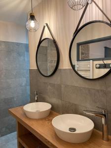 a bathroom with a sink and two mirrors on the wall at Maison La Tourelle in Baume-les-Dames