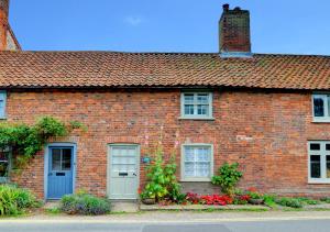 a brick house with a blue door and flowers at Angel Cottage in Burnham Market