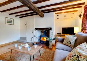 a living room with a couch and a table and a fireplace at Angel Cottage in Burnham Market